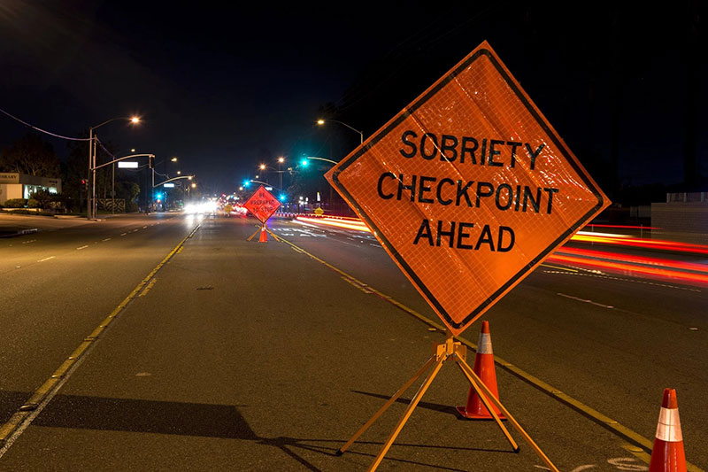 Street with "sobriety checkpoint ahead" sign