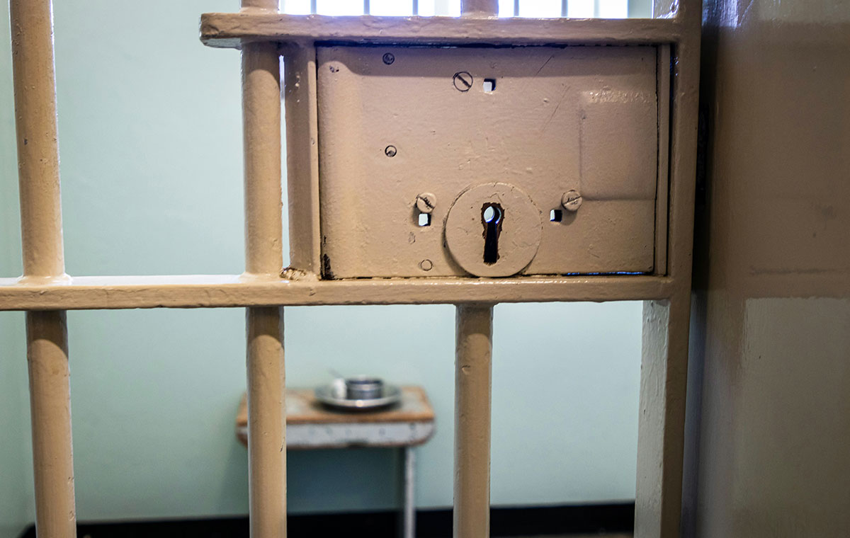 Jail or prison door, showing bars and lock, with look inside of cell